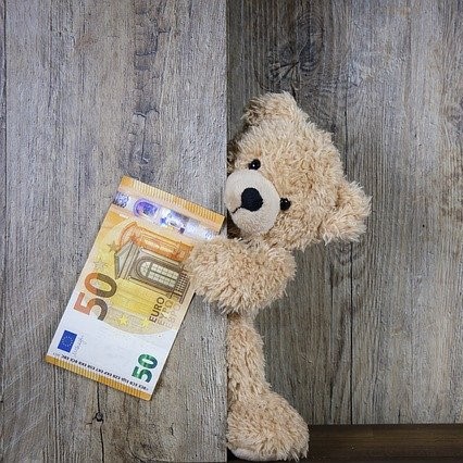 Ein süßer Teddybär, der einen 50€ Schen hält.